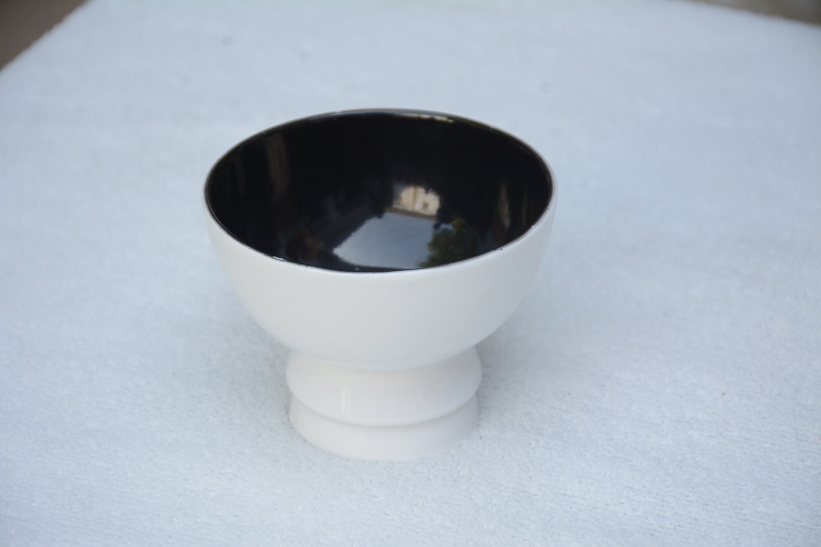 A small, two-toned ceramic or melamine bowl with a pedestal base.