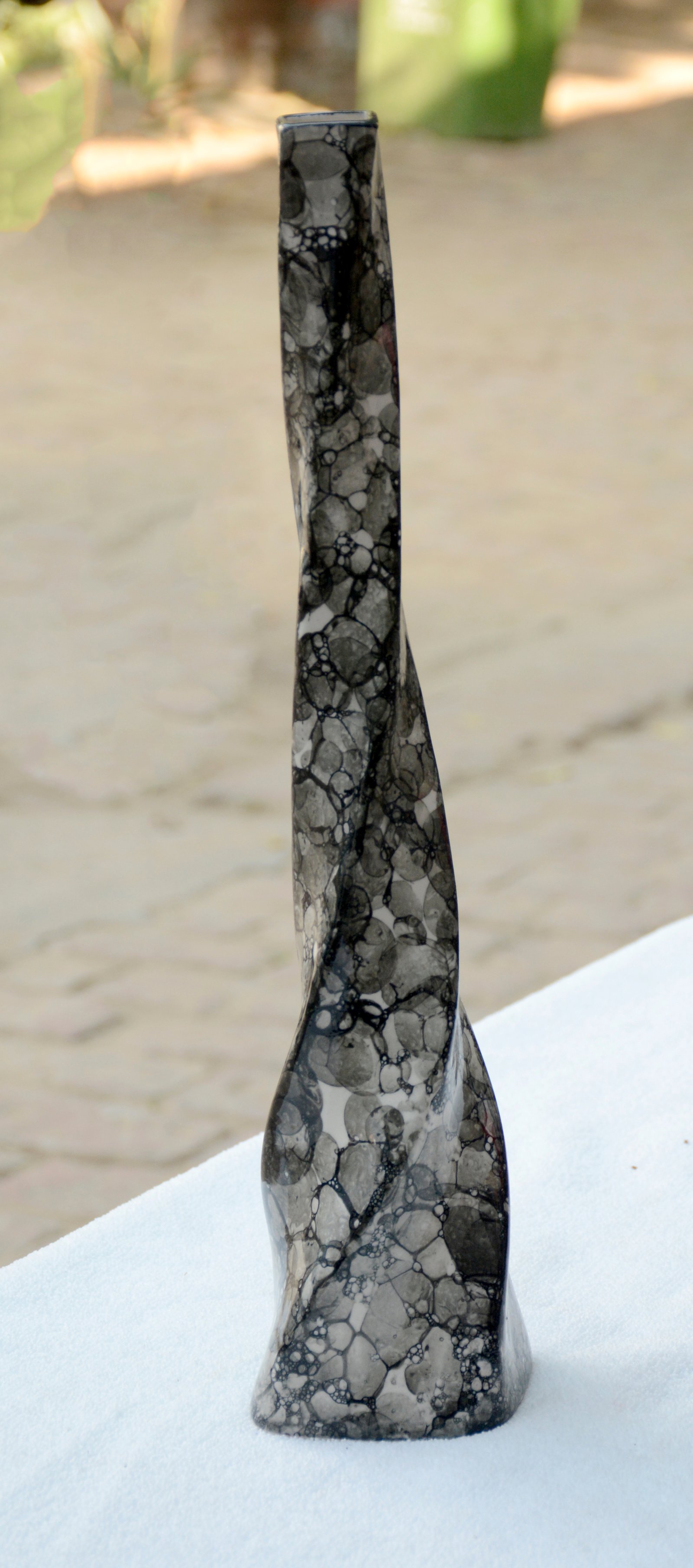 A tall, slender, and uniquely textured vase featuring a twisted design and a marbled, stone-like appearance.