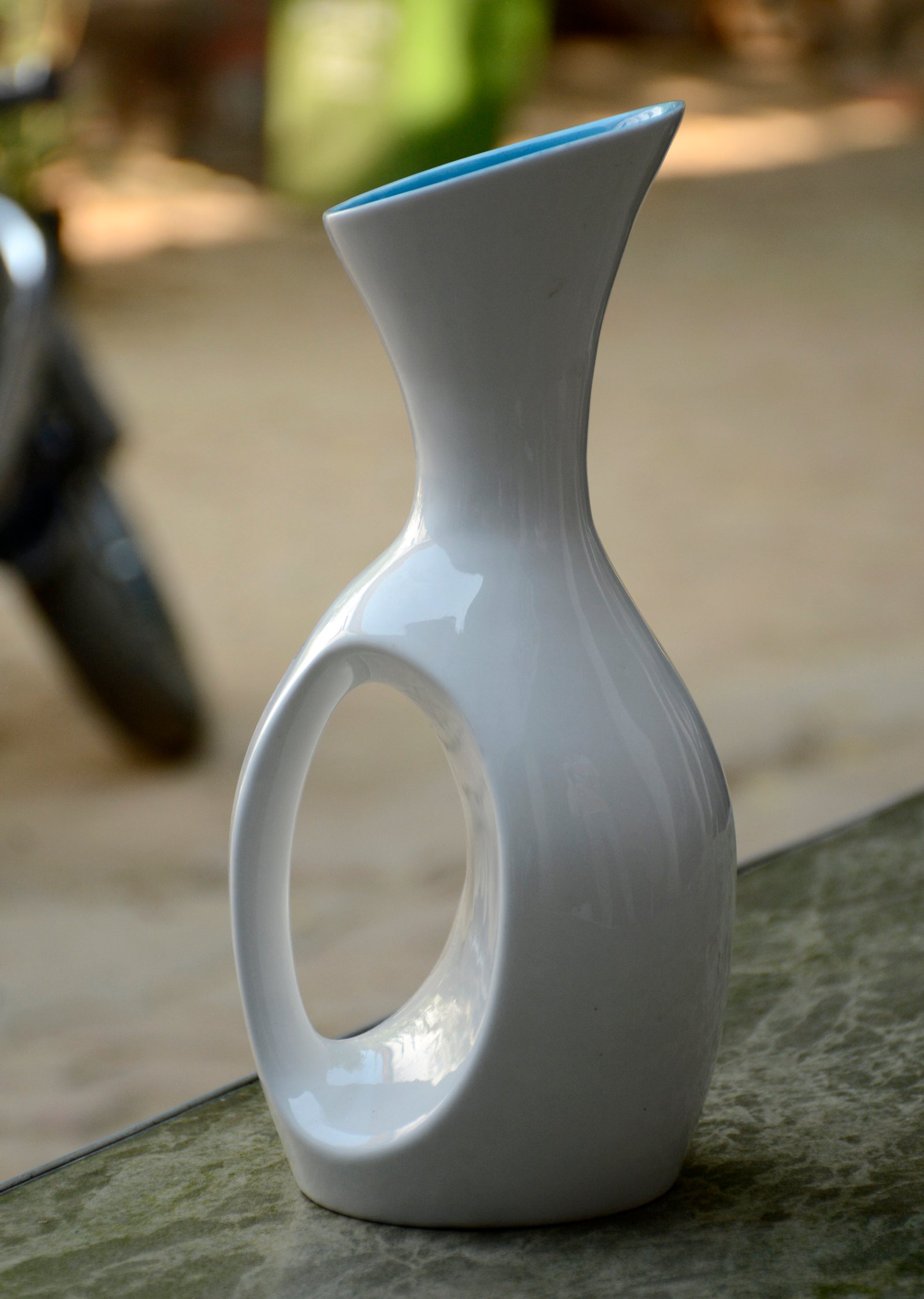 A sleek, modern ceramic vase with a unique handle design and a minimalist aesthetic.