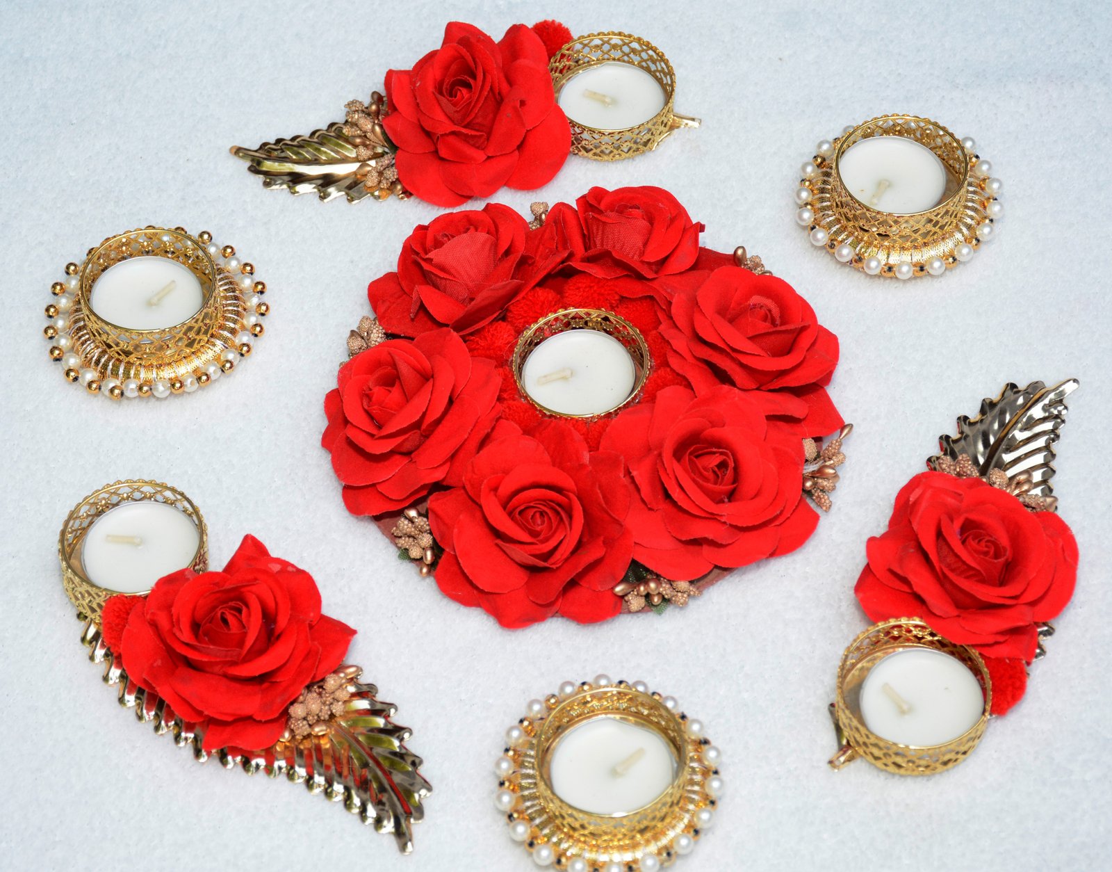 A set of seven decorative tea light holders arranged in a rangoli-inspired layout, featuring a combination of floral motifs and metallic accents.